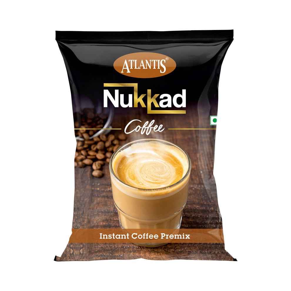 Atlantis Nukkad instant coffee premix packet with a glass of frothy coffee and coffee beans on wooden surface